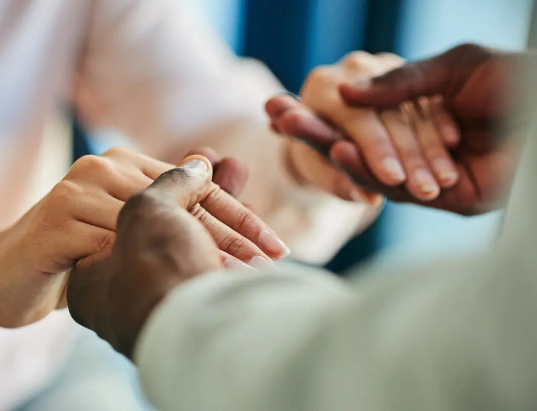 Close-up of two pairs of hands, one helping the other, suggesting support or connection.