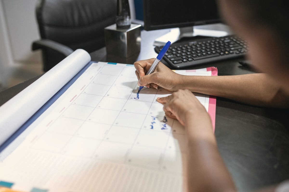 A person writing on a desk calendar