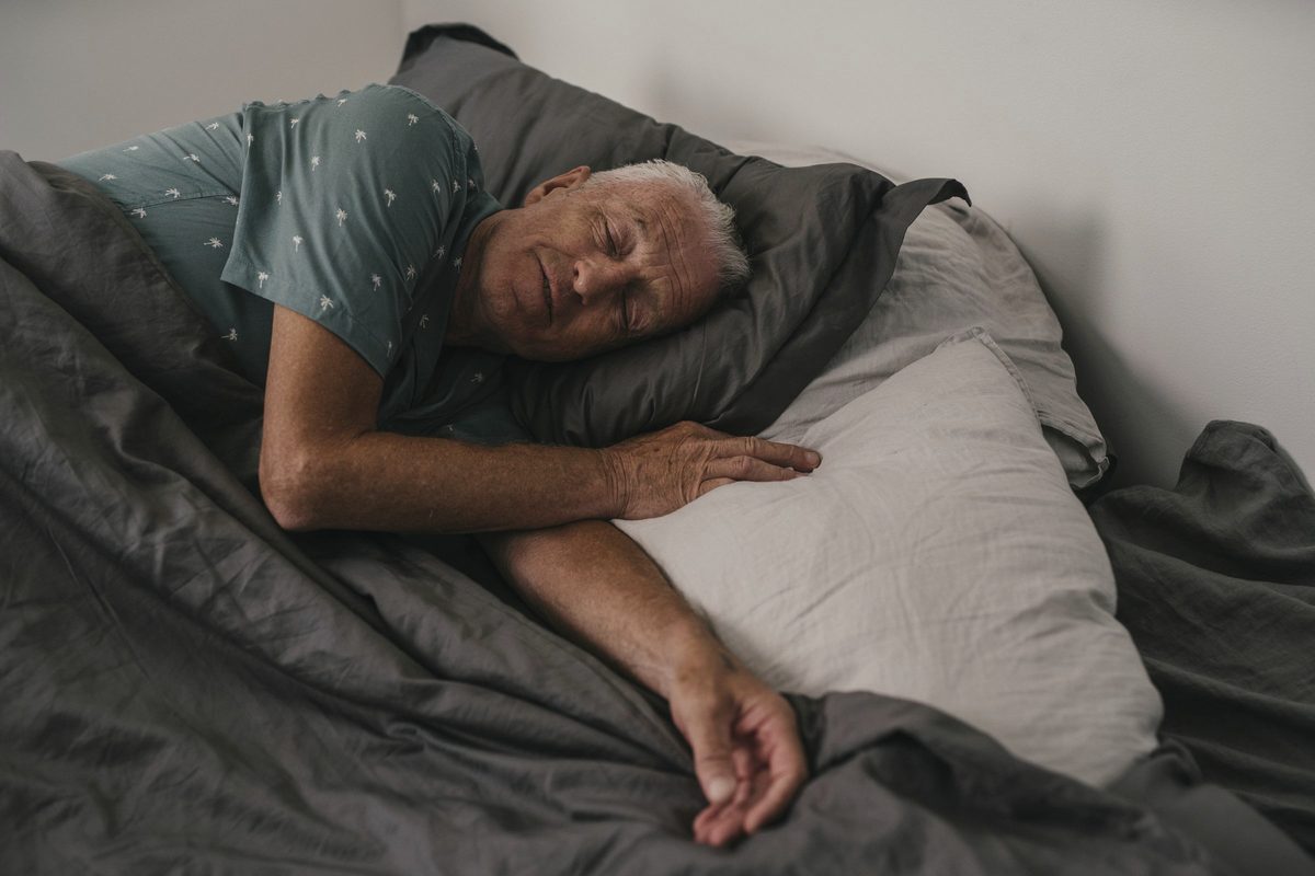 An elderly man sleeping on the bed