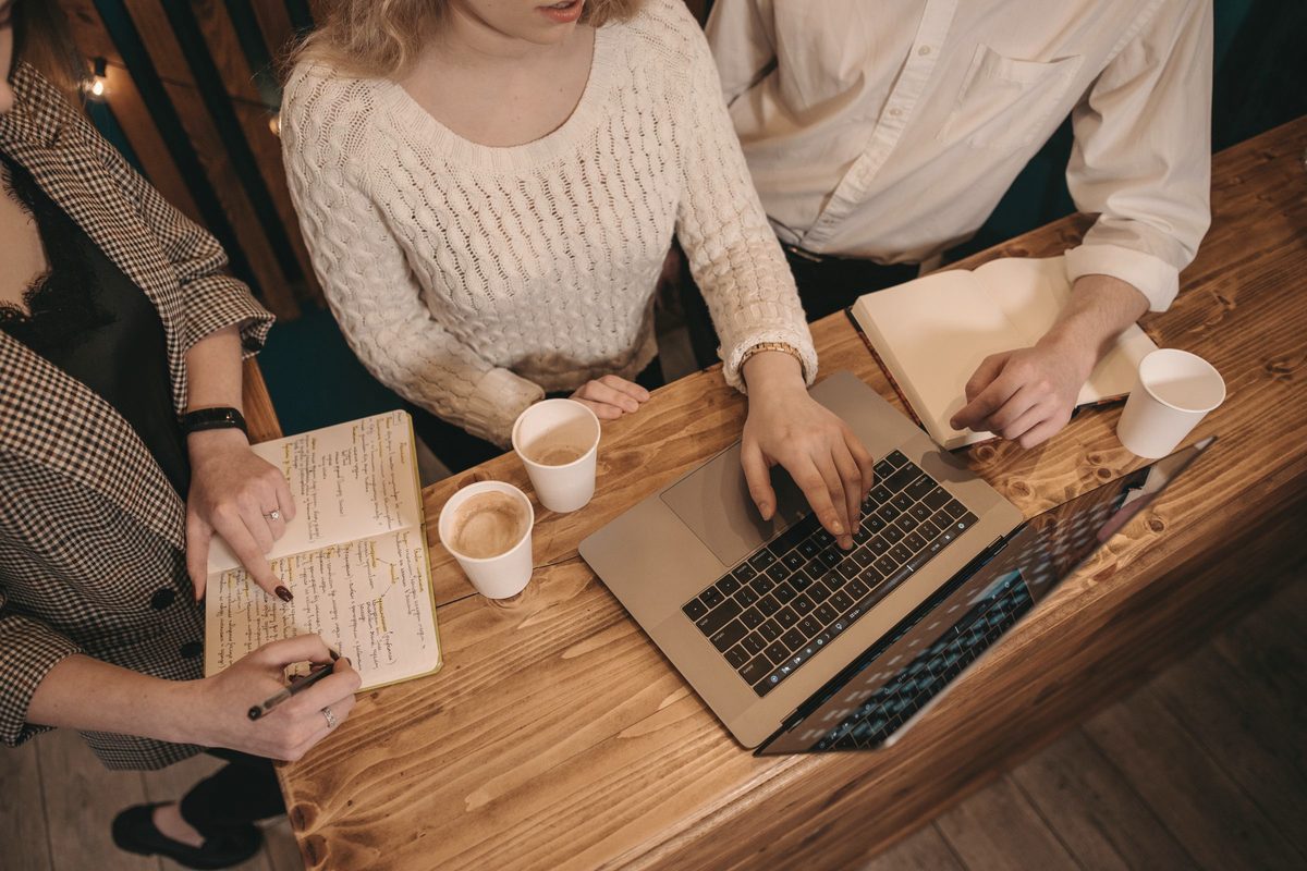 Group discussing ideas around a wooden table with laptops