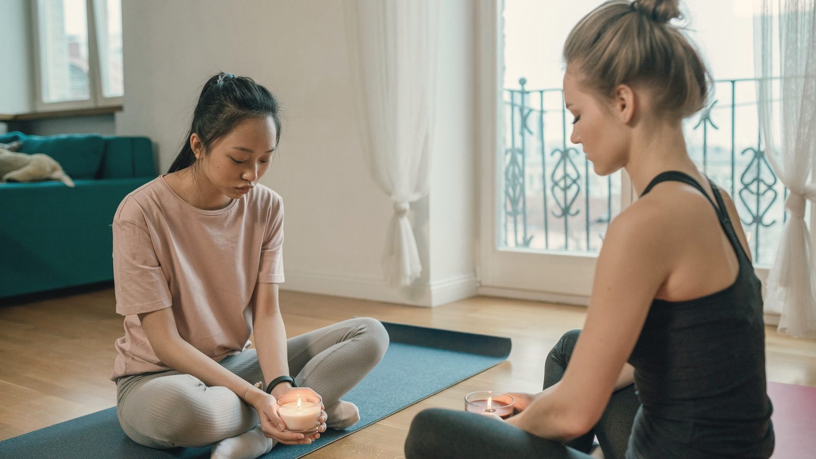 Two women meditating with candles at home