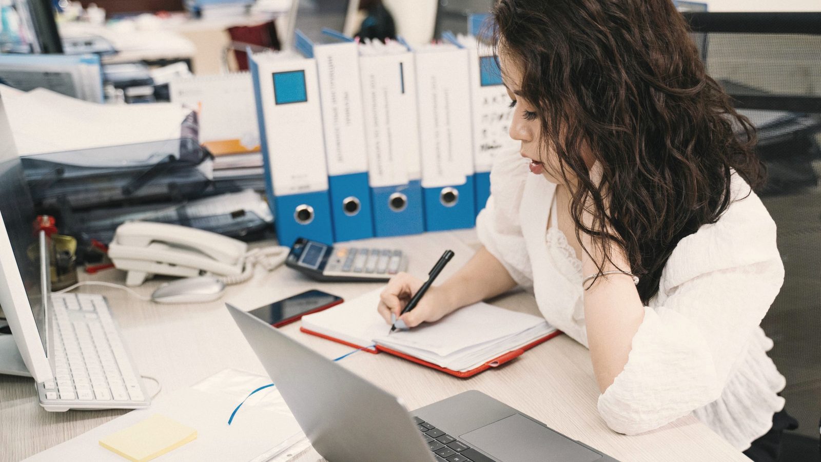 Woman working through her paperwork beside a laptop