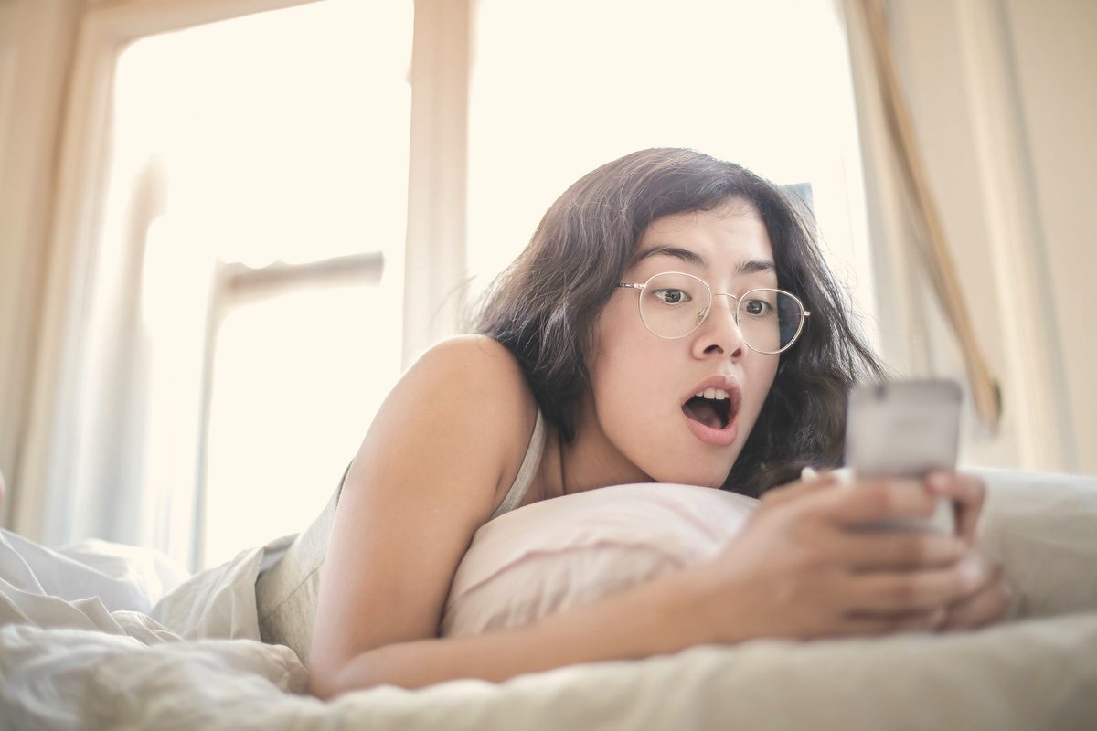 Woman lying in bed looking at her phone