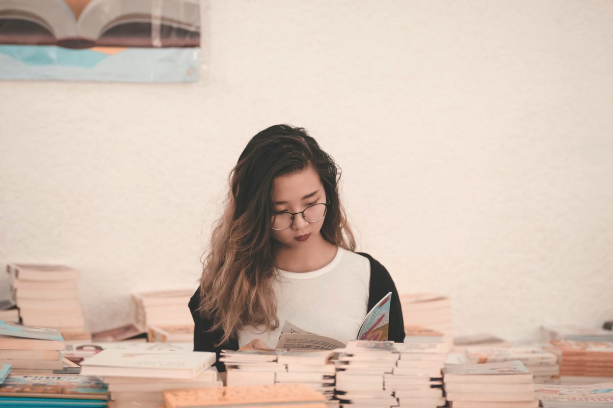 Woman reading at a table surrounded by books