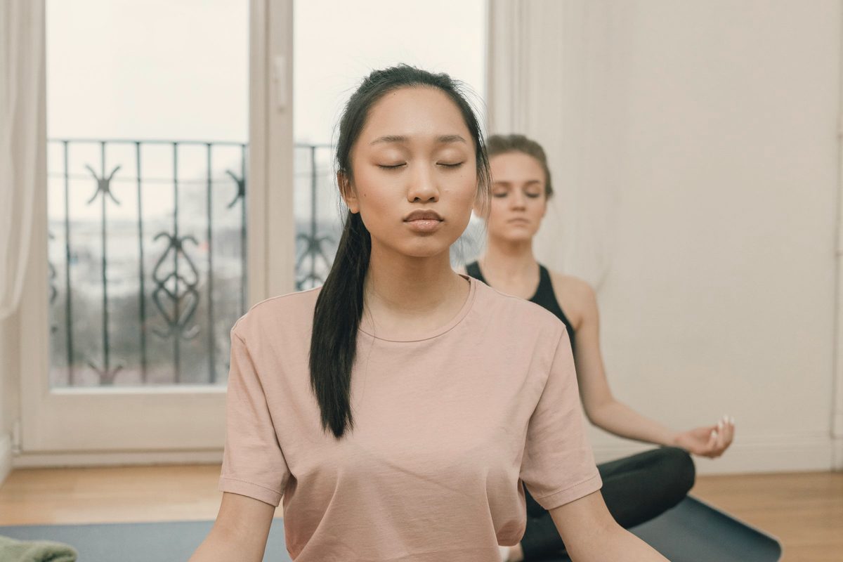 Women sitting on yoga mats with their eyes closed