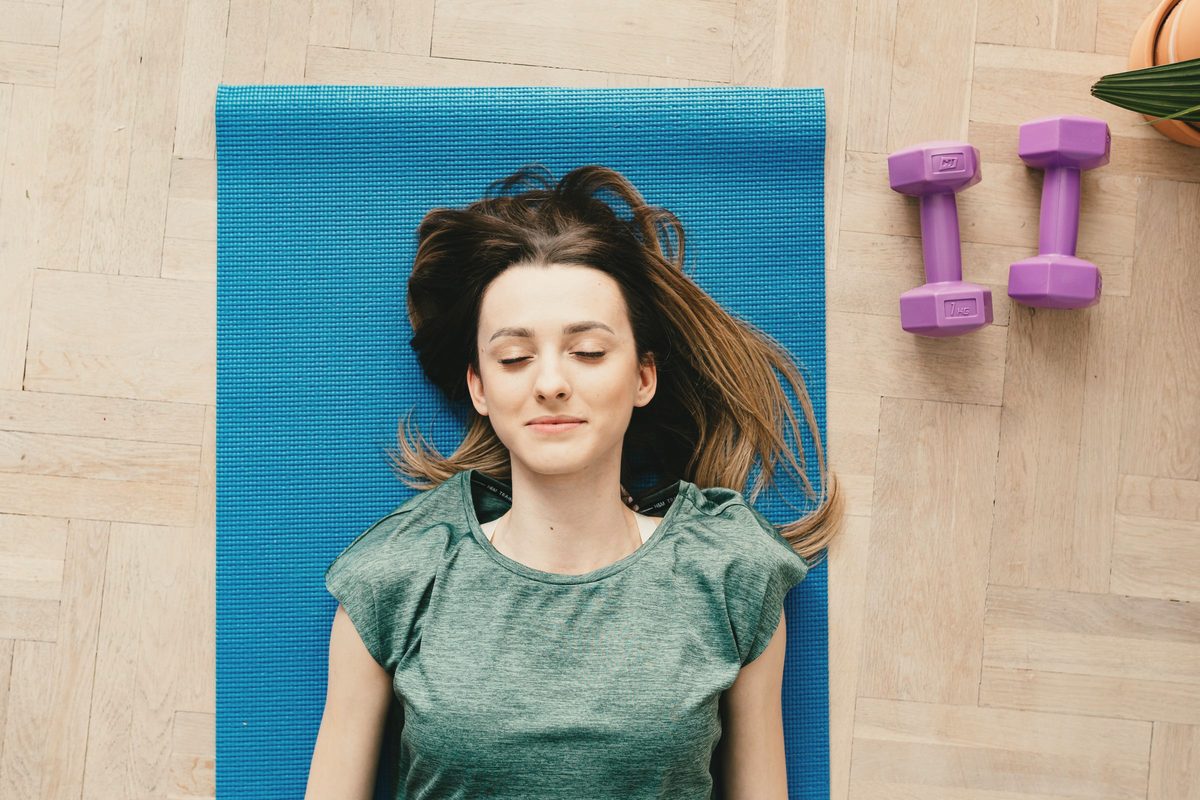 Smiling woman lying on a yoga mat with her eyes closed
