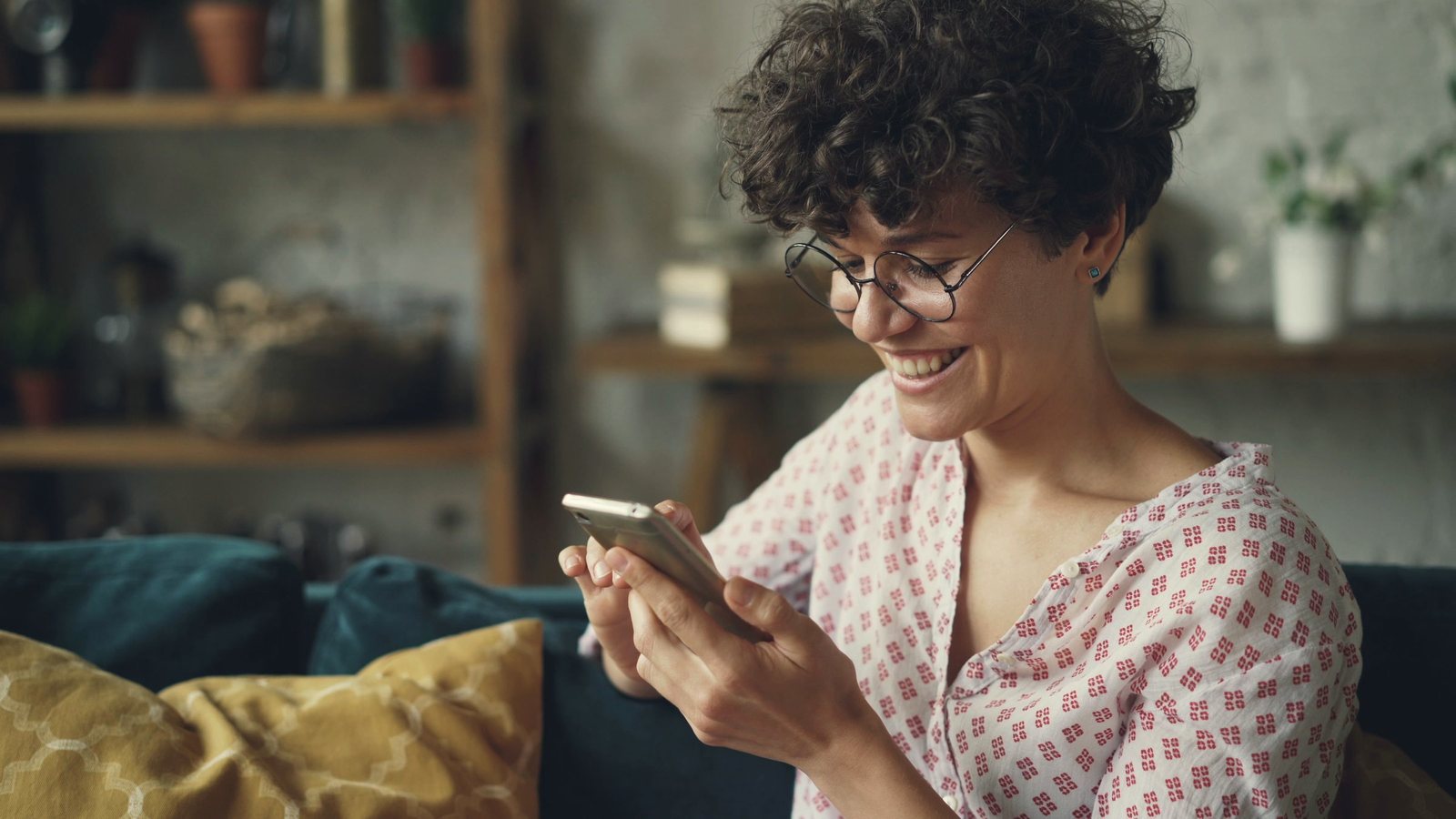 Smiling woman using her smartphone on a sofa at home