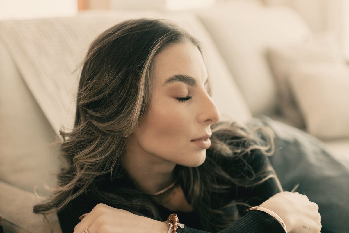 Woman relaxing on a sofa with eyes closed in soft window light