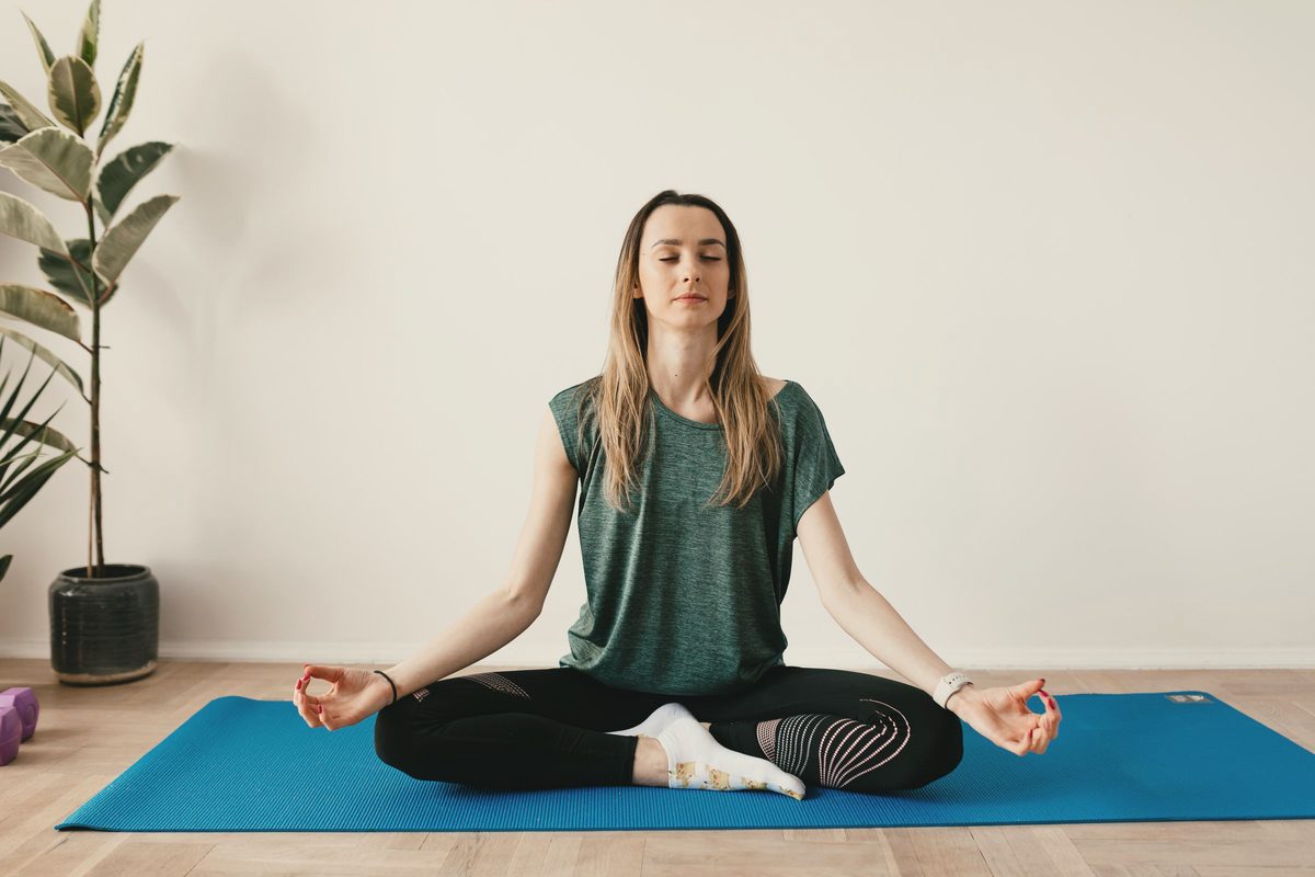 Woman sitting cross-legged on a mat with her eyes closed