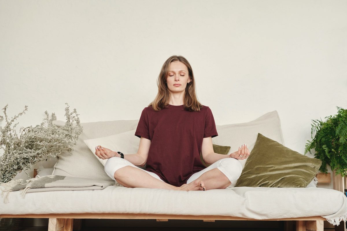 Woman sitting cross-legged on a sofa breathing slowly