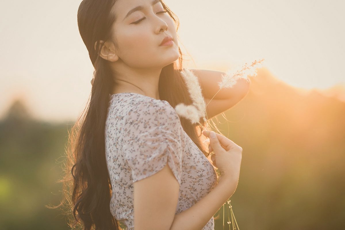 Woman standing with her eyes closed in warm sunlight