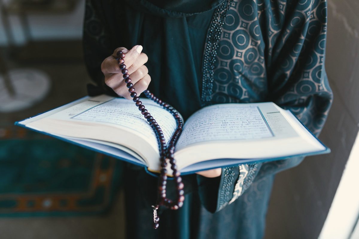Person holding prayer beads and a book