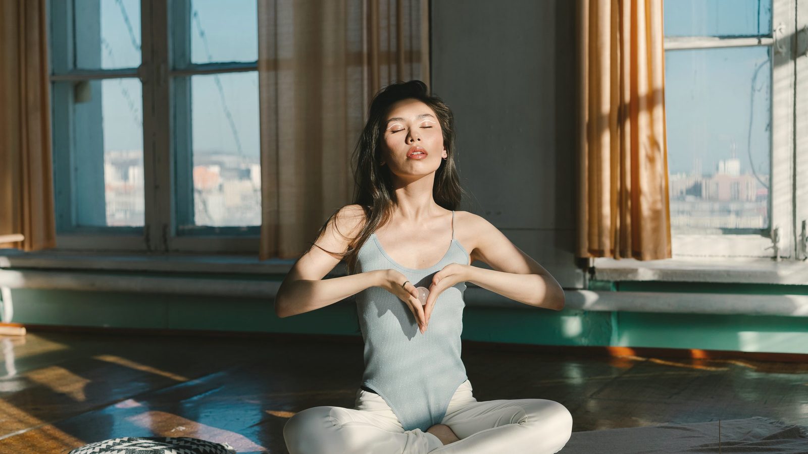 Woman meditating on the floor by a sunny window