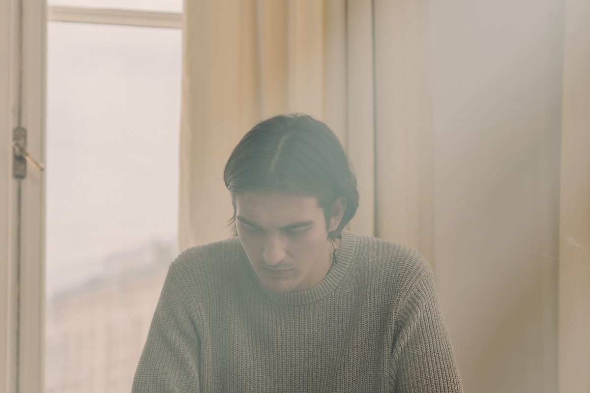 Man reading on a desk while sitting by the window