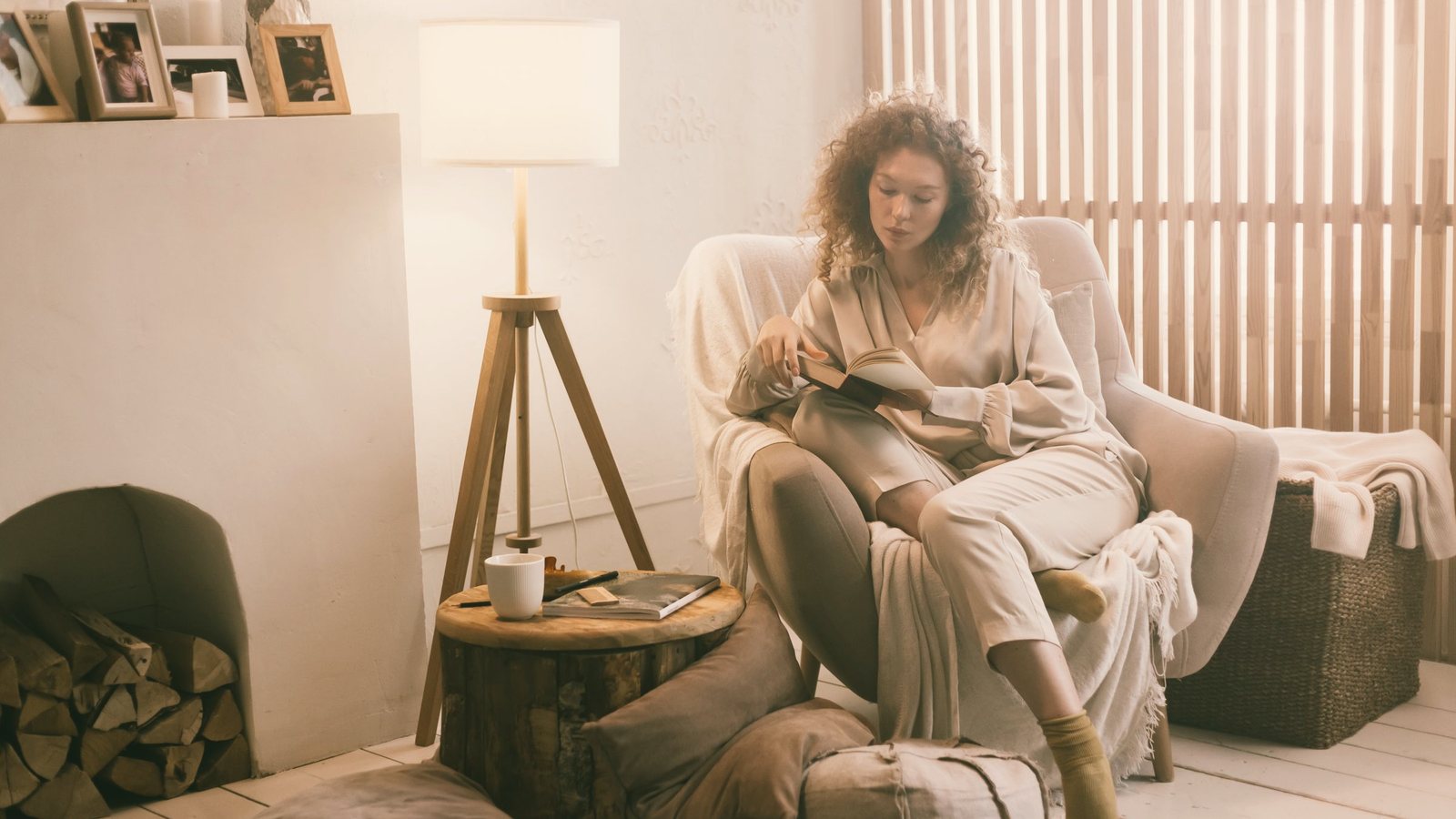 Woman reading a book in a lamp-lit armchair during her evening wind down routine