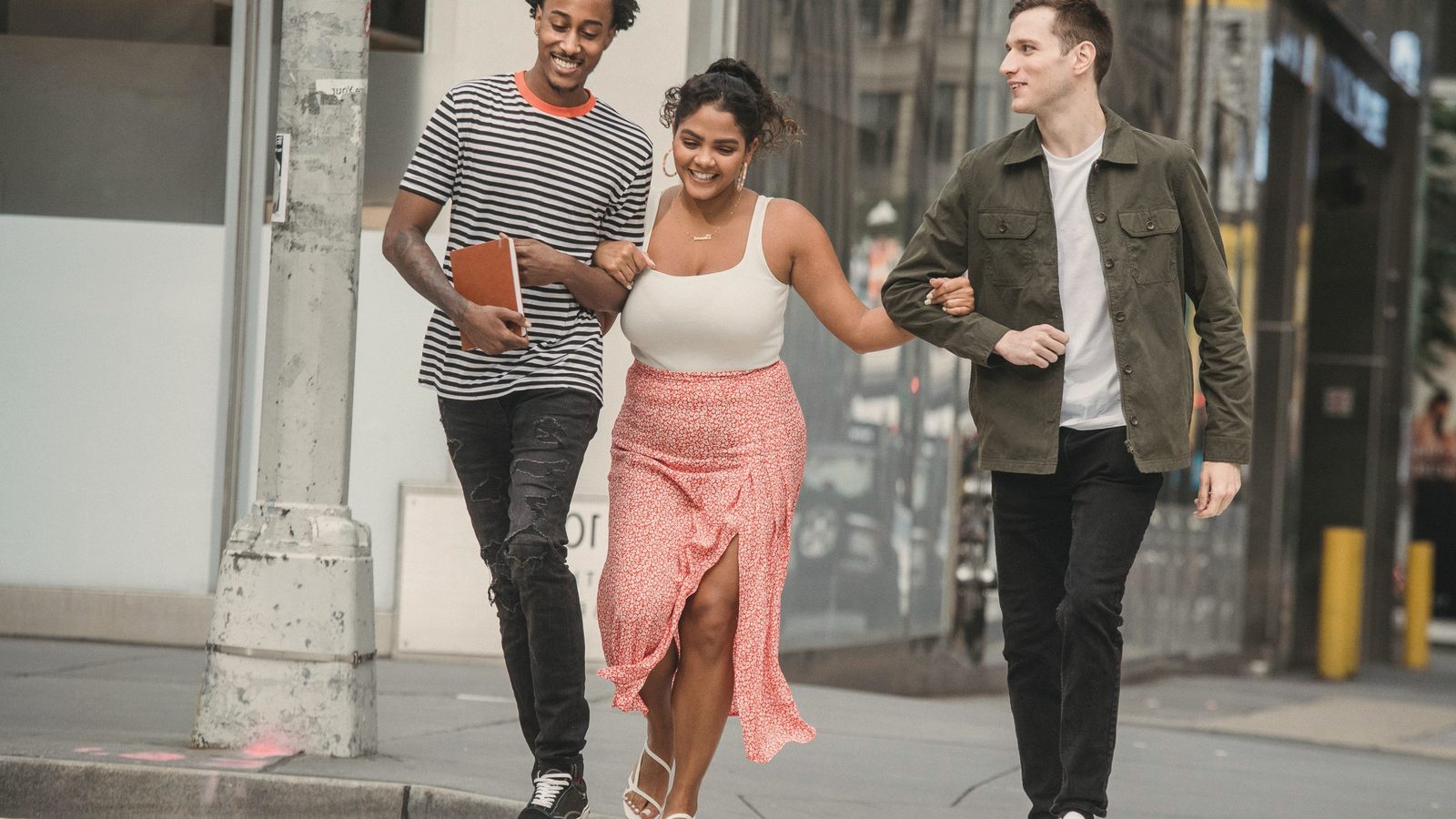 Happy friends smiling while walking on zebra crossing