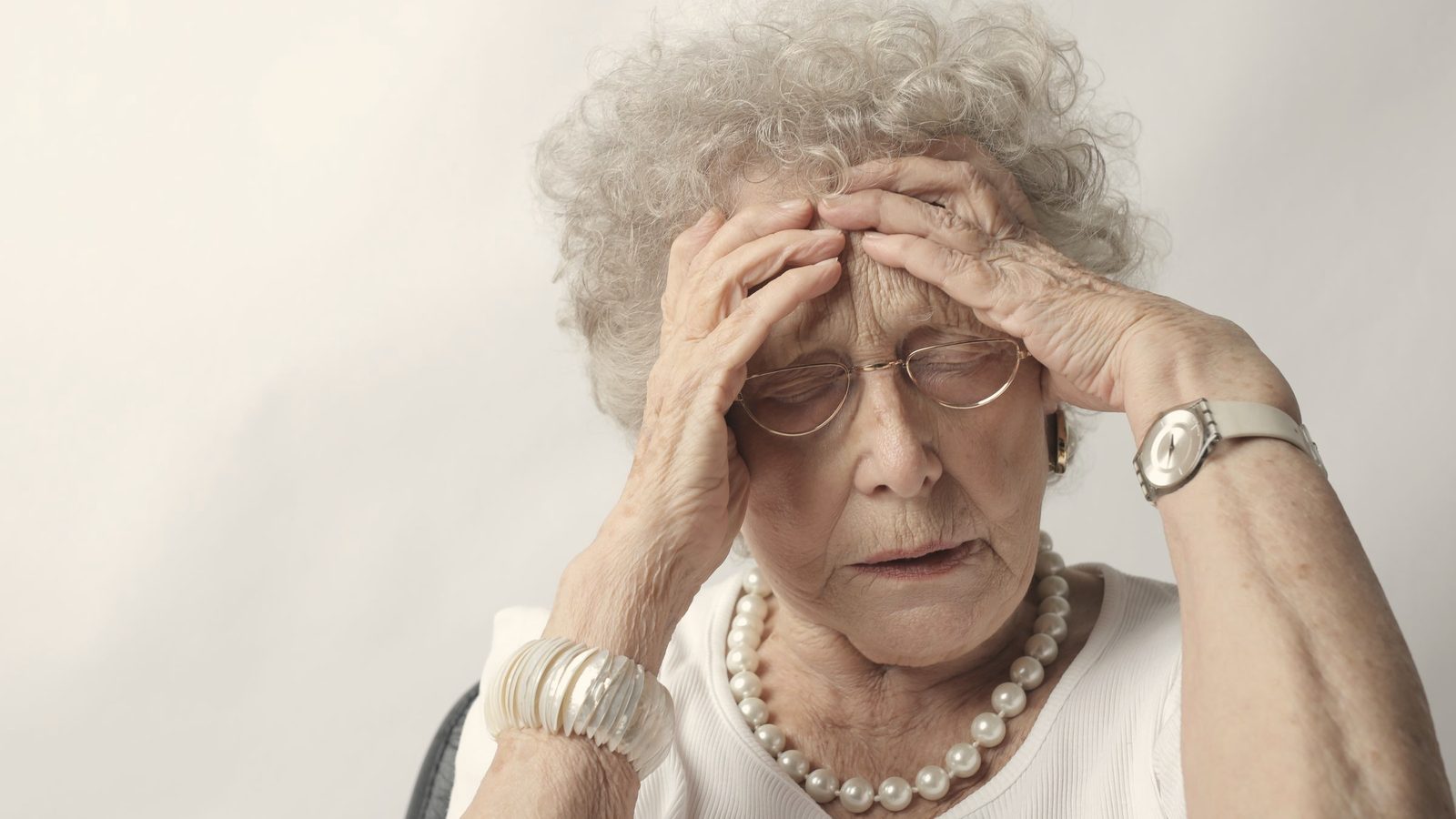 Older woman holding her head with a worried look