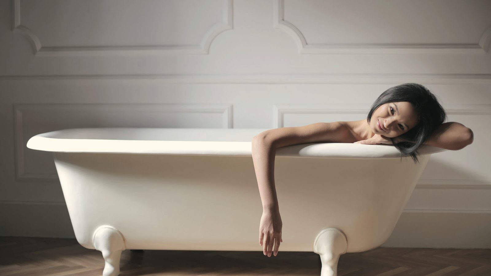 Cheerful young lady relaxing in bath in modern bathroom