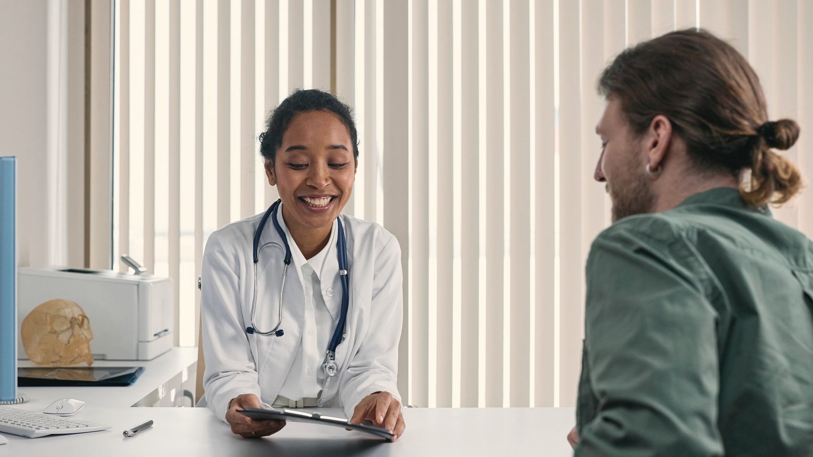 Woman working at a white desk with a laptop and open notebooks