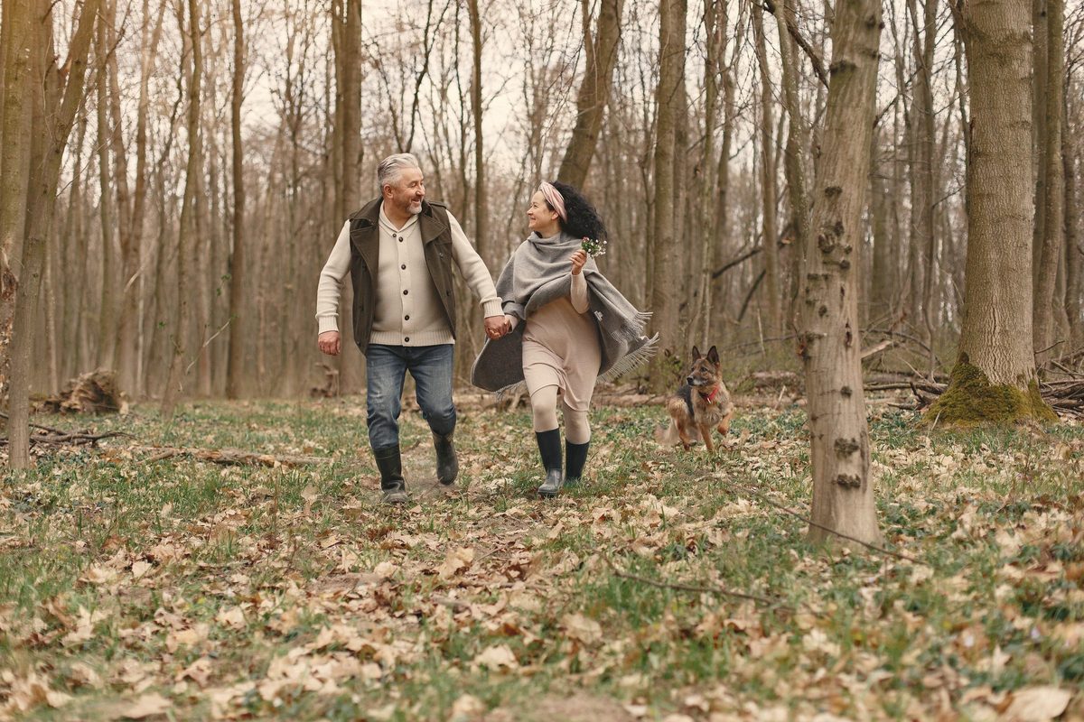 Older couple walking through the woods with their dog
