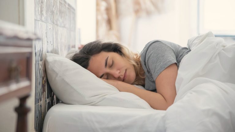 Woman sleeping soundly on white pillows in a bright bedroom