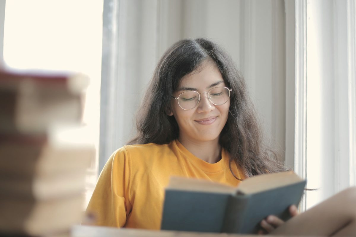 Smiling woman reading a book by the window