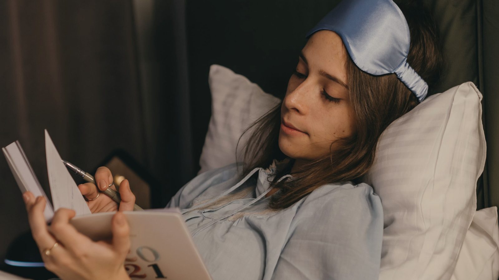 A woman writing on her journal while lying in bed