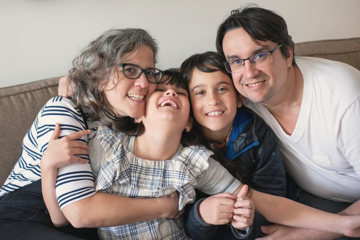 Family hugging and laughing together on the sofa
