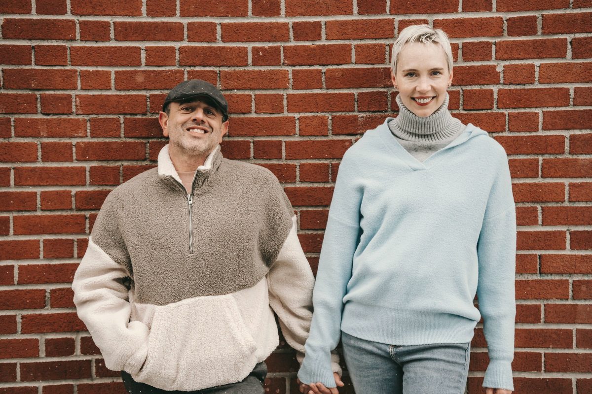 Smiling couple holding hands against a brick wall