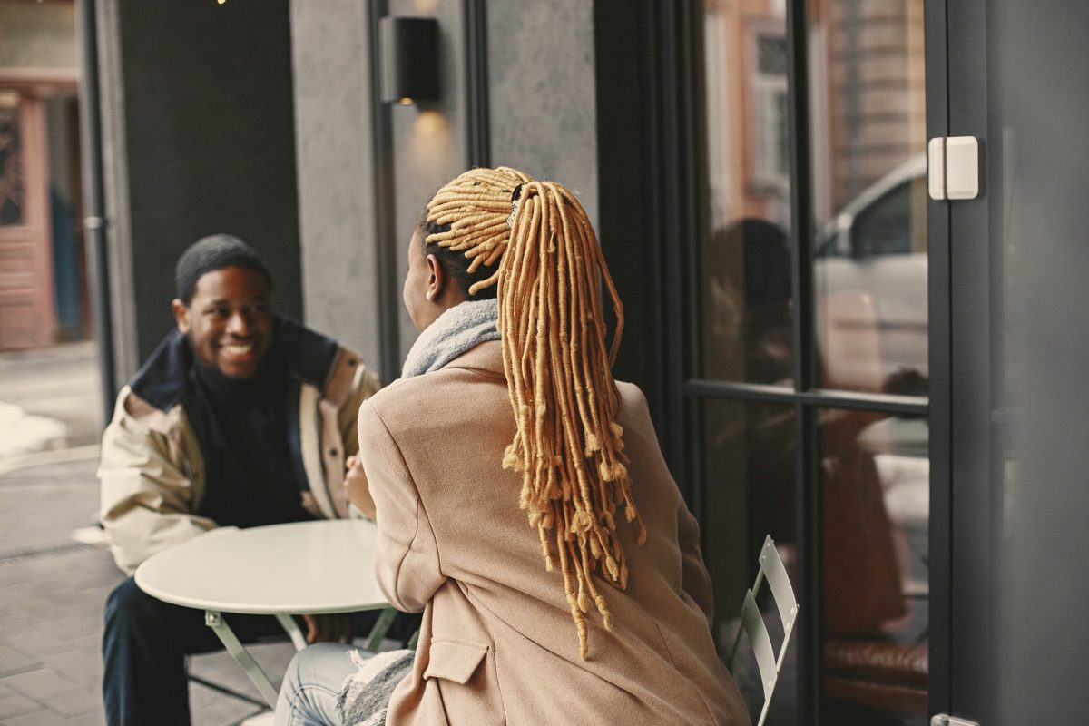 Two friends talking and laughing at an outdoor cafe table