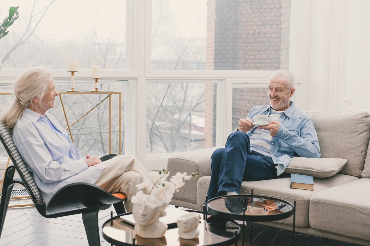 Senior couple relaxing on armchairs and chatting in a sunlit lounge room