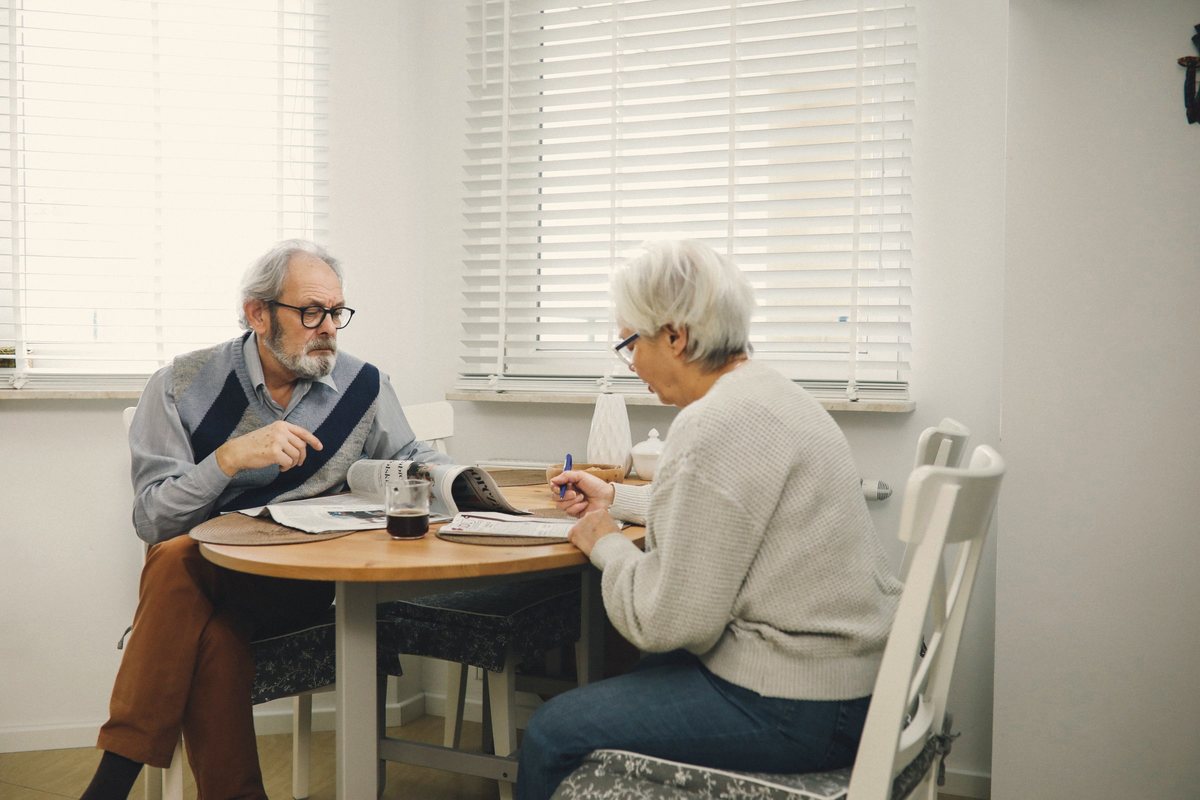 Older couple sitting together at a round dining table in a bright room