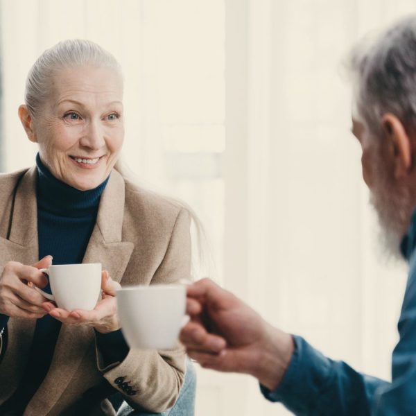 Older woman and man sharing coffee and conversation in a bright living room
