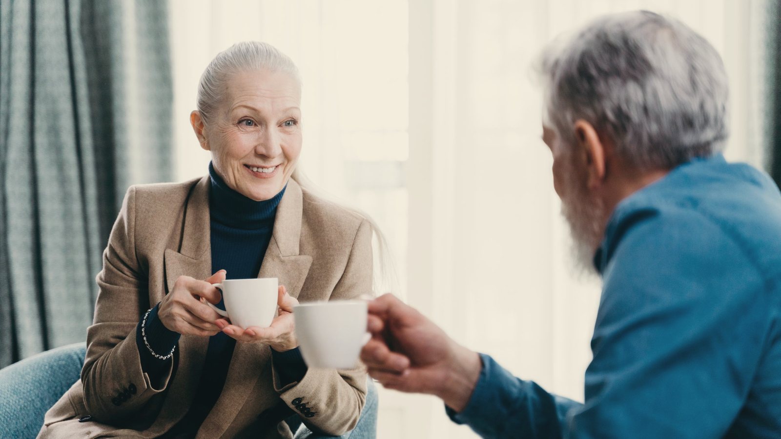 Older woman and man sharing coffee and conversation in a bright living room