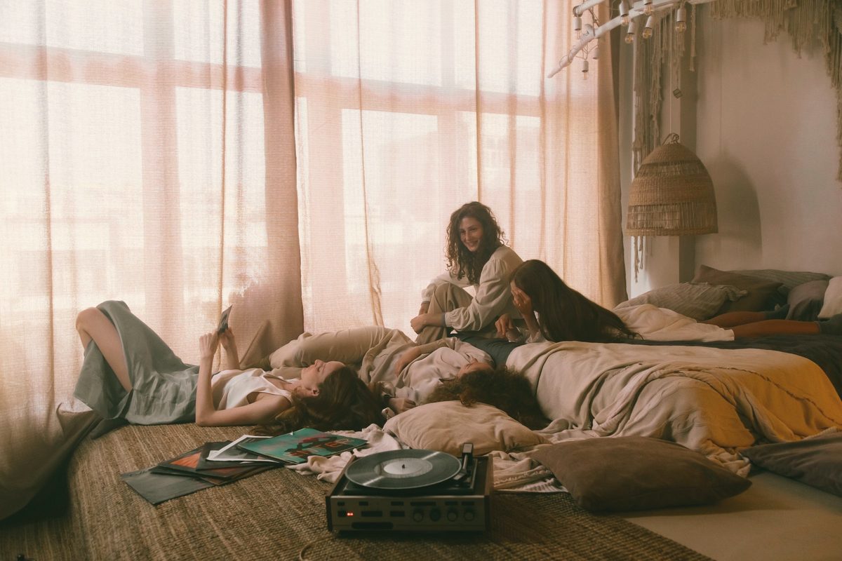 Friends laughing together on a bed at a sleepover