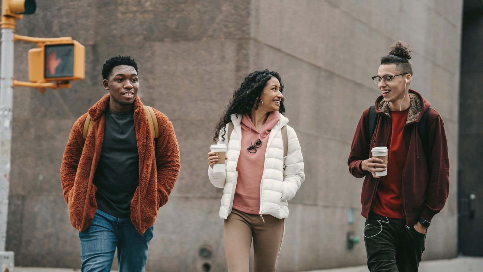Friends laughing as they walk down the street with coffee