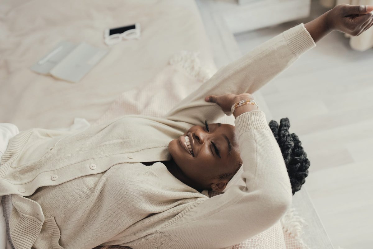 A smiling woman stretching in bed