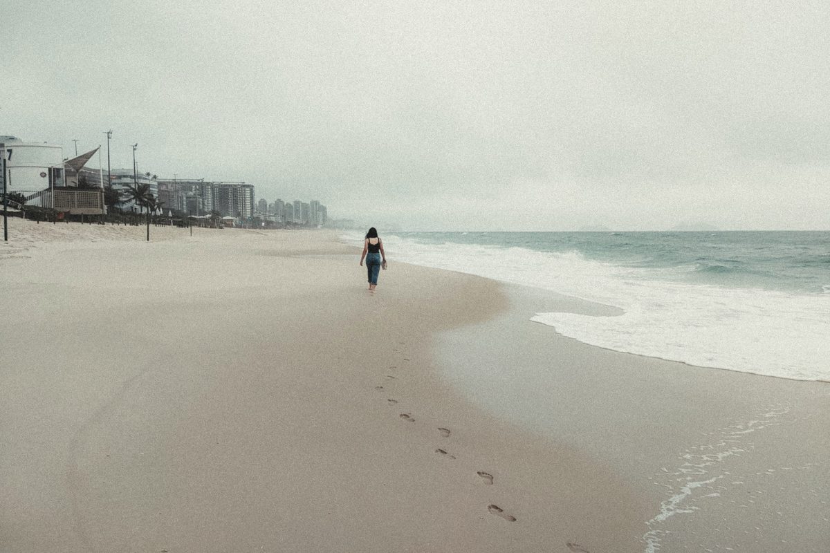 Person walking alone along the water at the beach