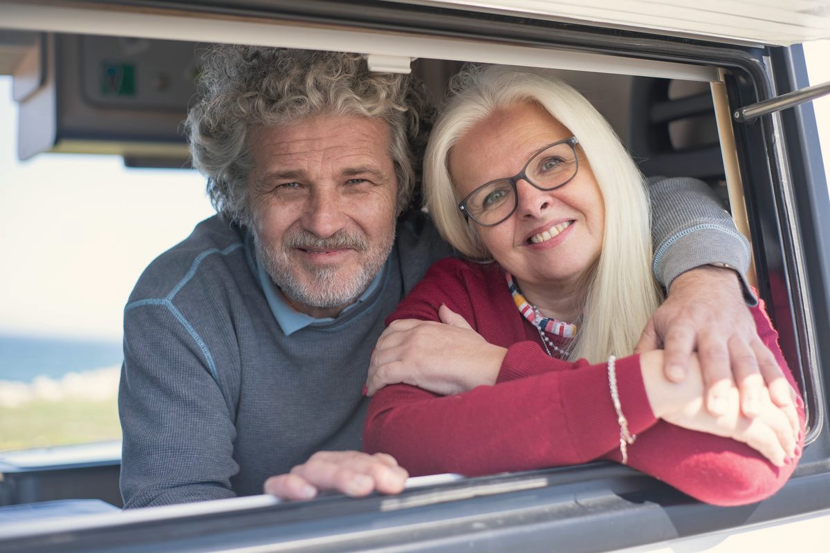 Older couple smiling together from a car window