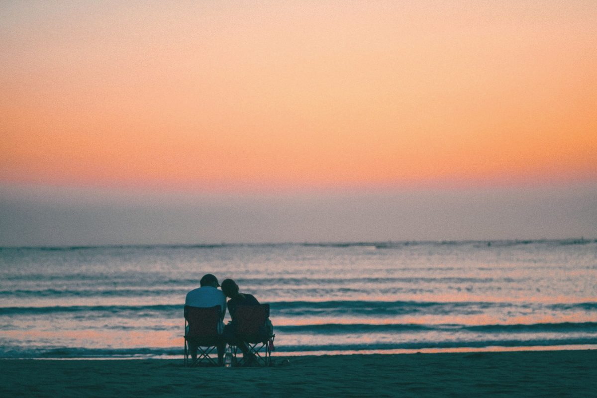 Couple sitting on the beach watching the sunset