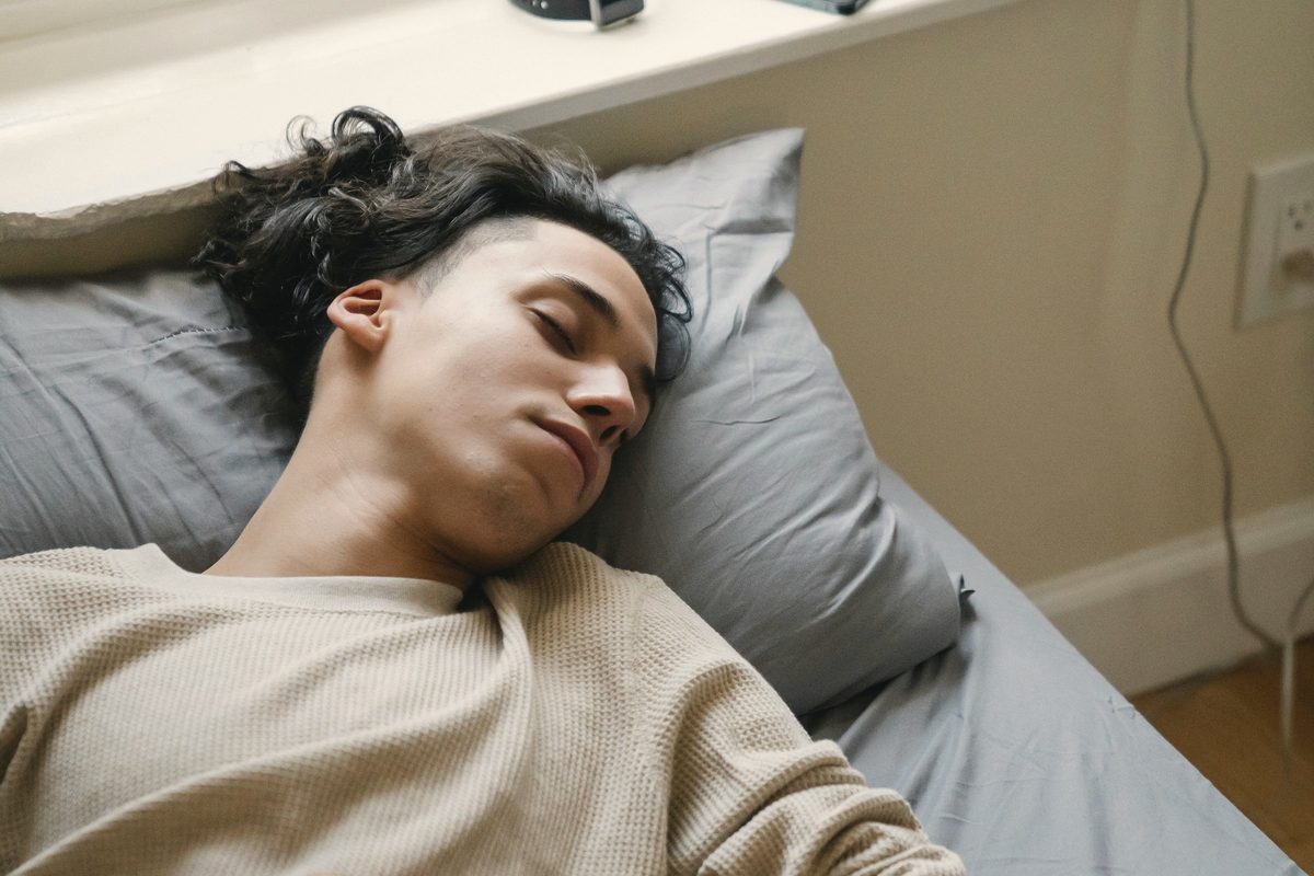 Young man sleeping on bed in morning