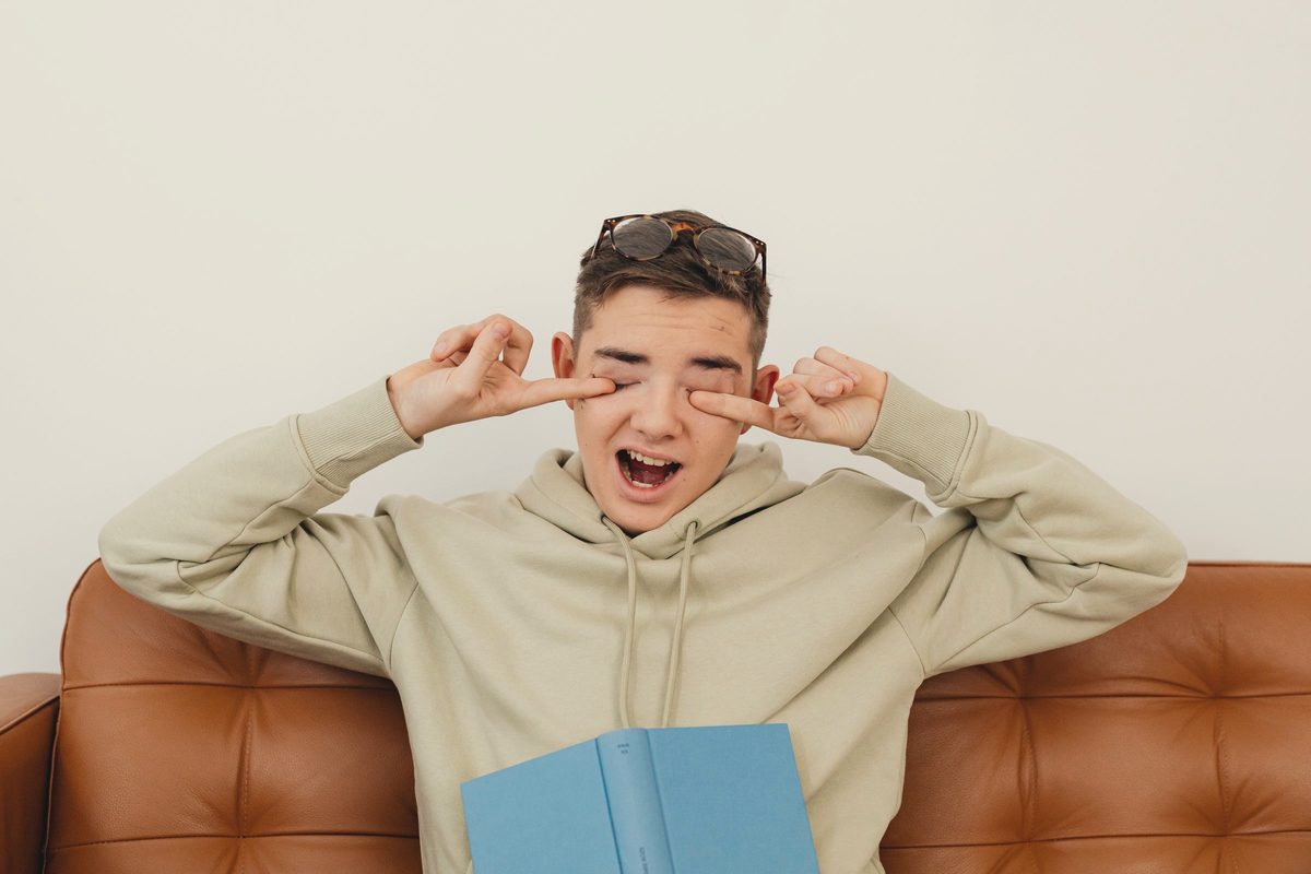 A man yawning while rubbing eyes with fingers