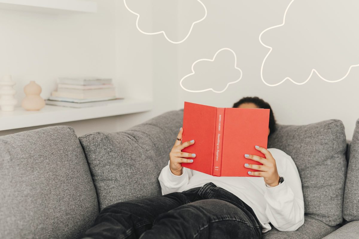 A person lying on the sofa while reading a book