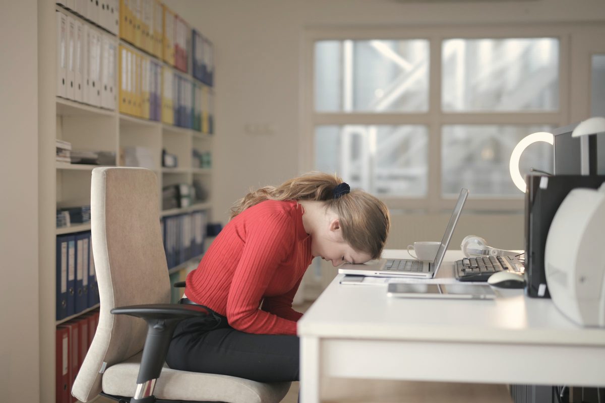 Woman slumped over her laptop at a home desk