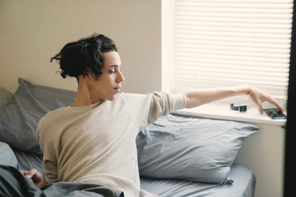 Young man stretching in bed in the morning