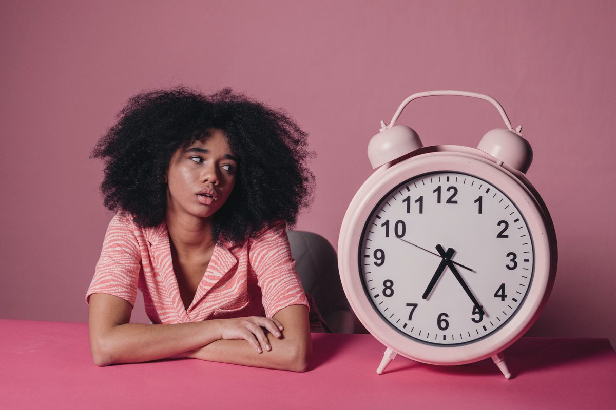Woman looking at a big pink alarm clock