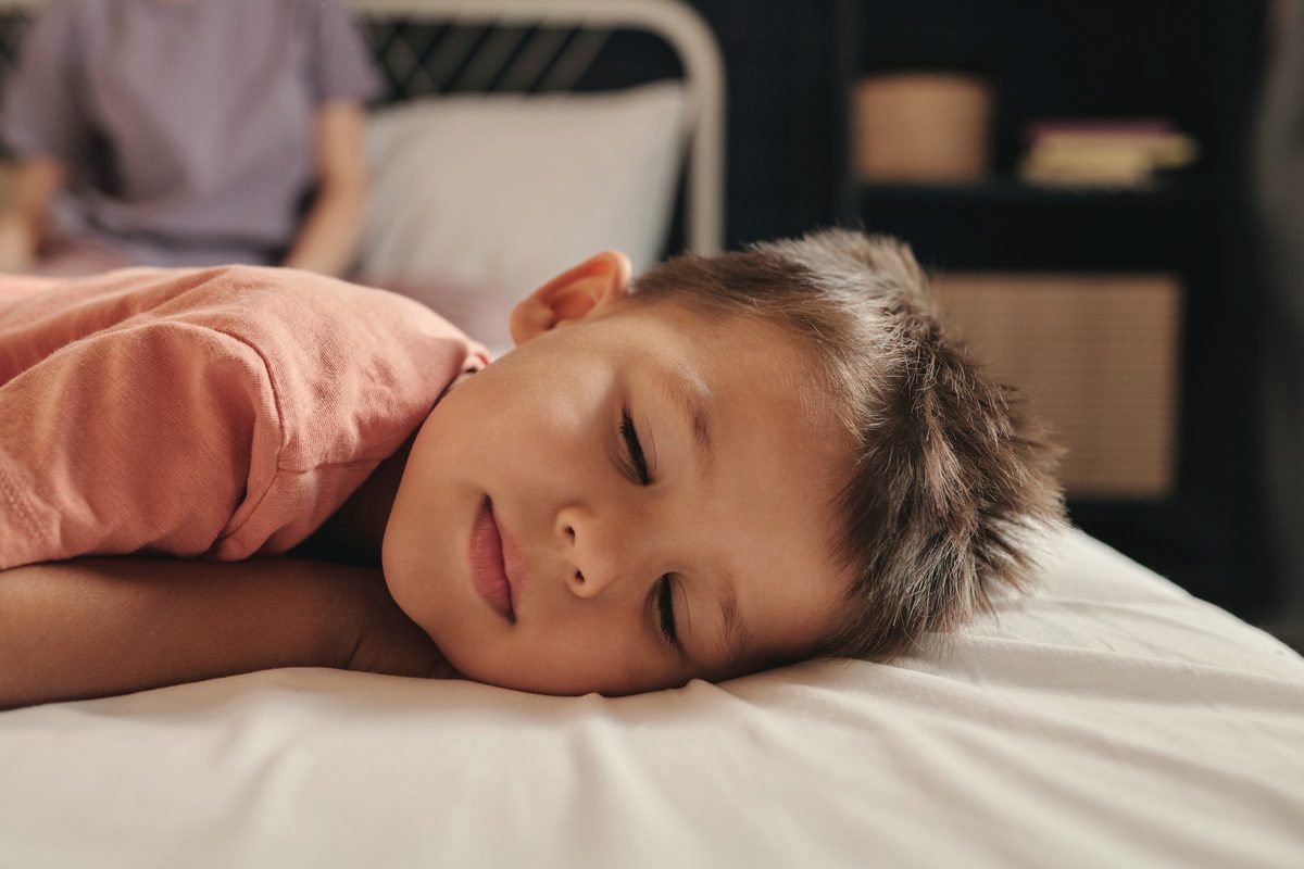 Selective focus photo of a boy in a salmon shirt sleeping