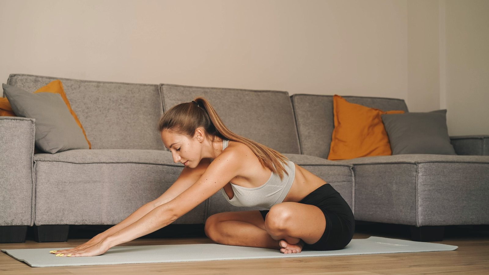 Woman doing a seated forward stretch on an exercise mat in her living room