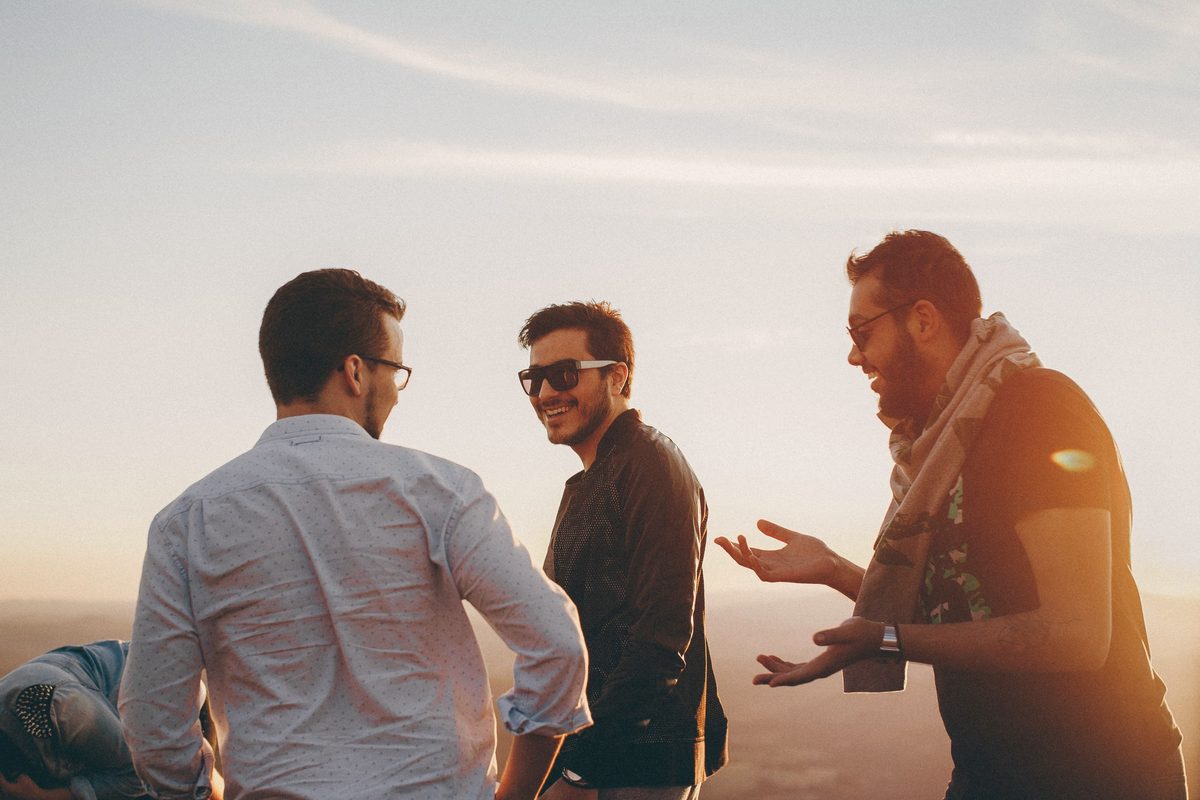 Three friends laughing together outdoors at sunset