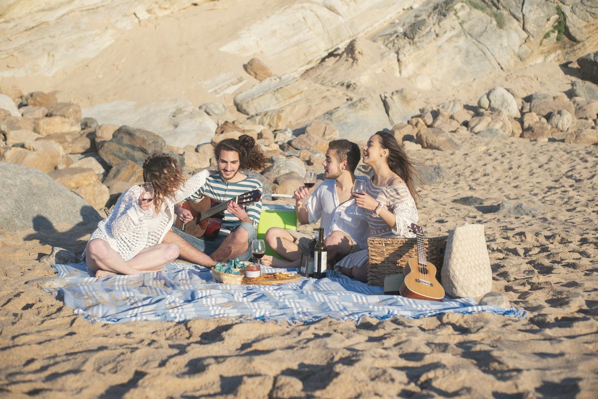 Friends having fun on a picnic blanket at the beach